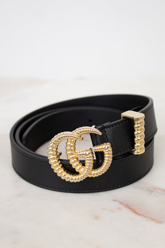 Black belt with a gold GG logo buckle on a marble surface