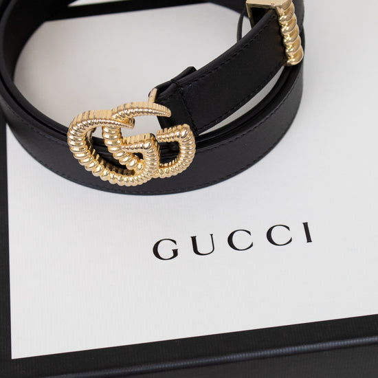 Black Gucci belt with gold hardware on a Gucci box