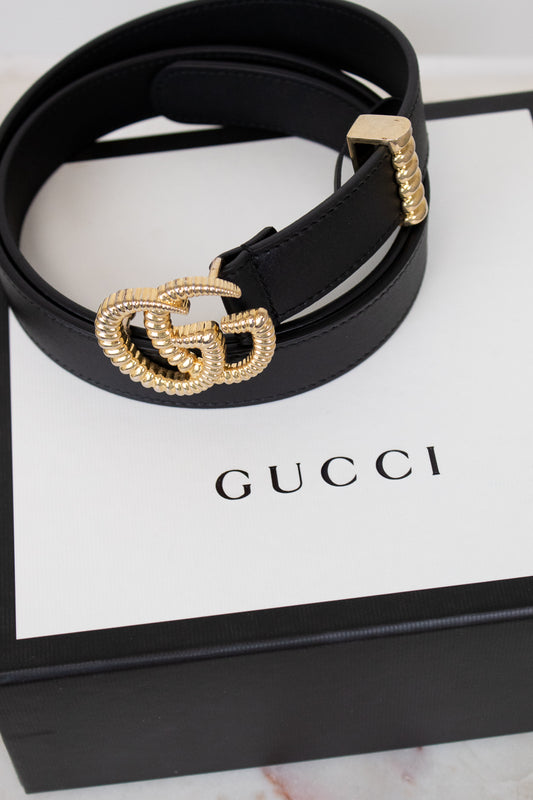 Black Gucci belt with gold hardware on a Gucci box