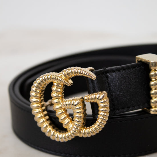 Black belt with a gold double G buckle on a light background