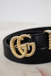 Black belt with a gold double G buckle on a light background