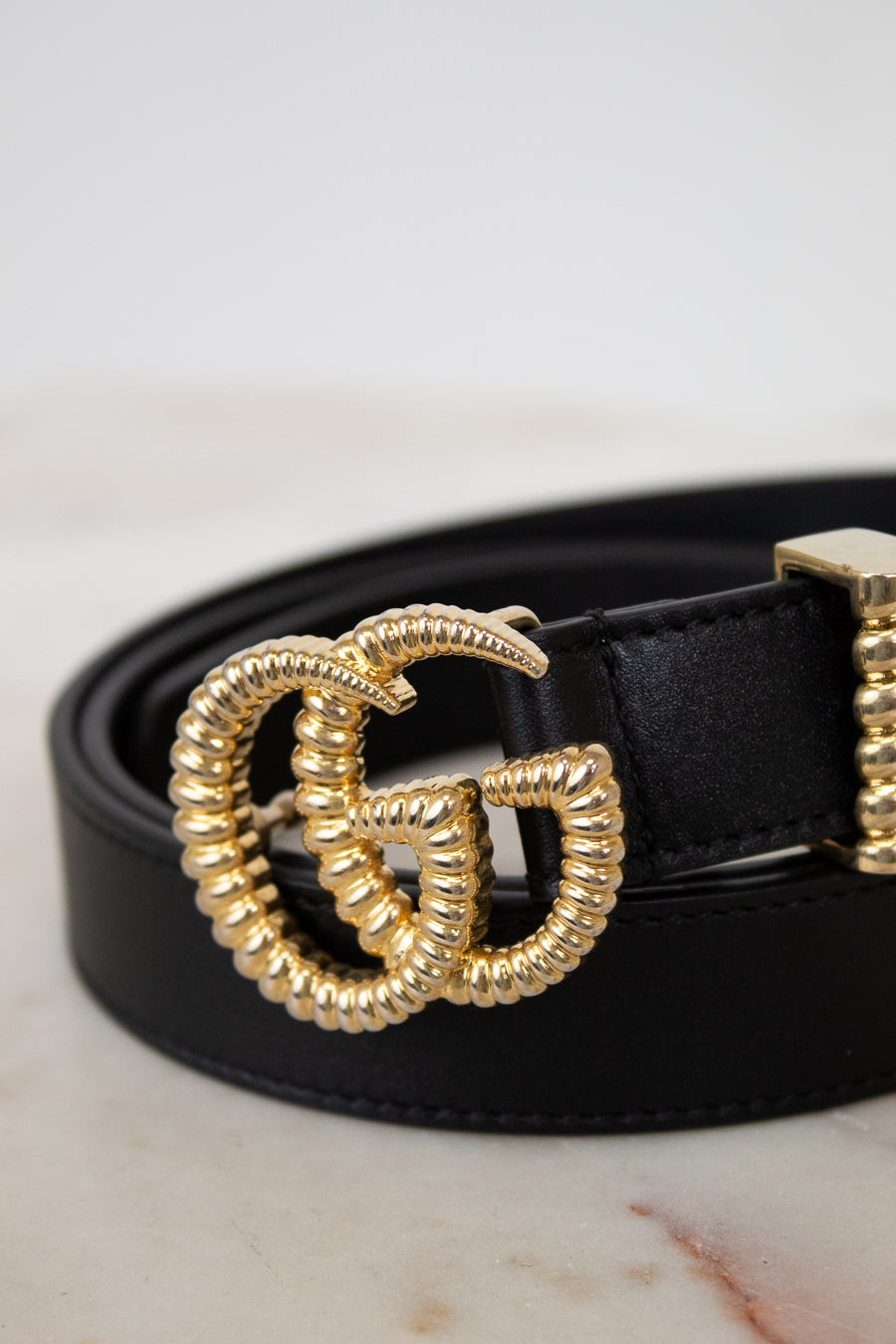 Black belt with a gold double G buckle on a light background