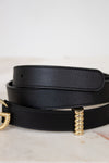 Black leather belt with gold hardware on a light background