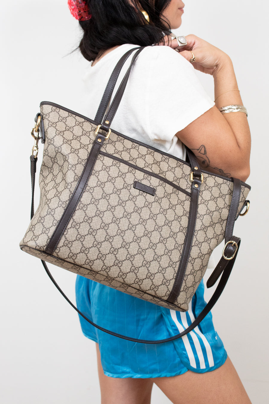 Person wearing a large beige and black handbag with a white background