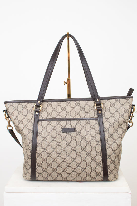 Beige and black handbag with a visible brand logo on a white background