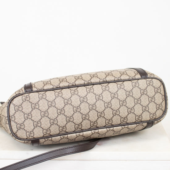 Beige patterned bag with brown strap on a white background
