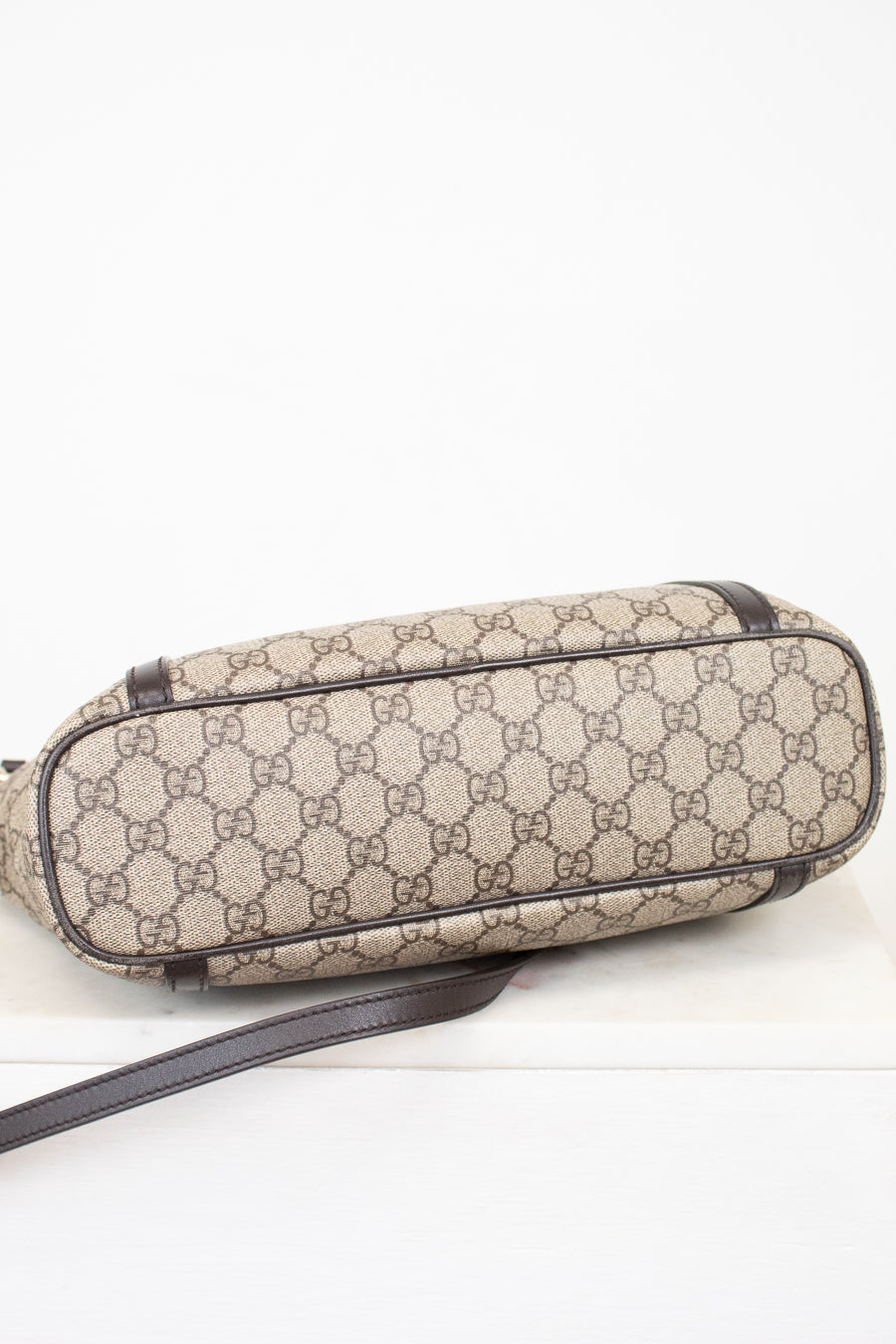 Beige patterned bag with brown strap on a white background