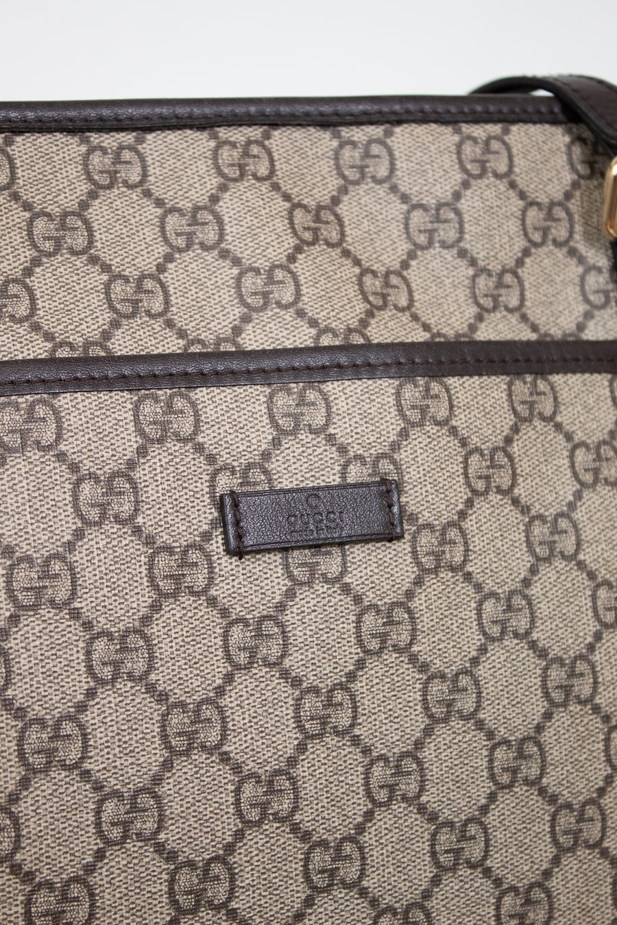 Gucci bag with monogram pattern and visible logo on a light gray background