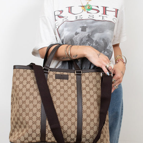 Person holding a patterned handbag wearing a graphic t-shirt with text.