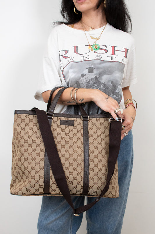 Person holding a patterned handbag wearing a graphic t-shirt with text.