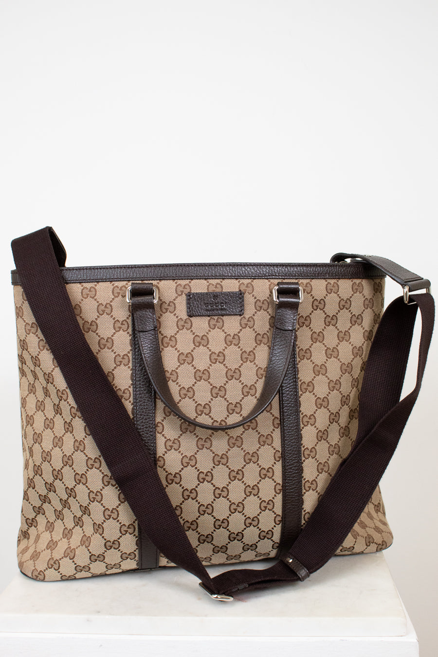 Beige and brown patterned handbag with a matching strap on a white background