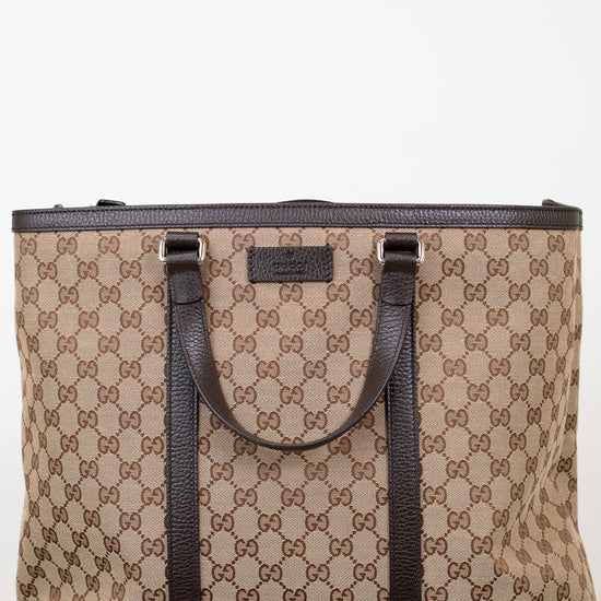 Beige and brown patterned tote bag with black handles on a white background