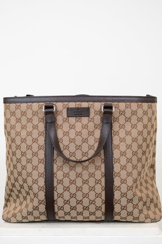 Beige and brown patterned tote bag with black handles on a white background