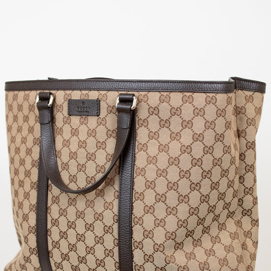 Beige and brown patterned tote bag with black handles on a white background