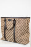 Beige and brown patterned tote bag with black handles on a white background