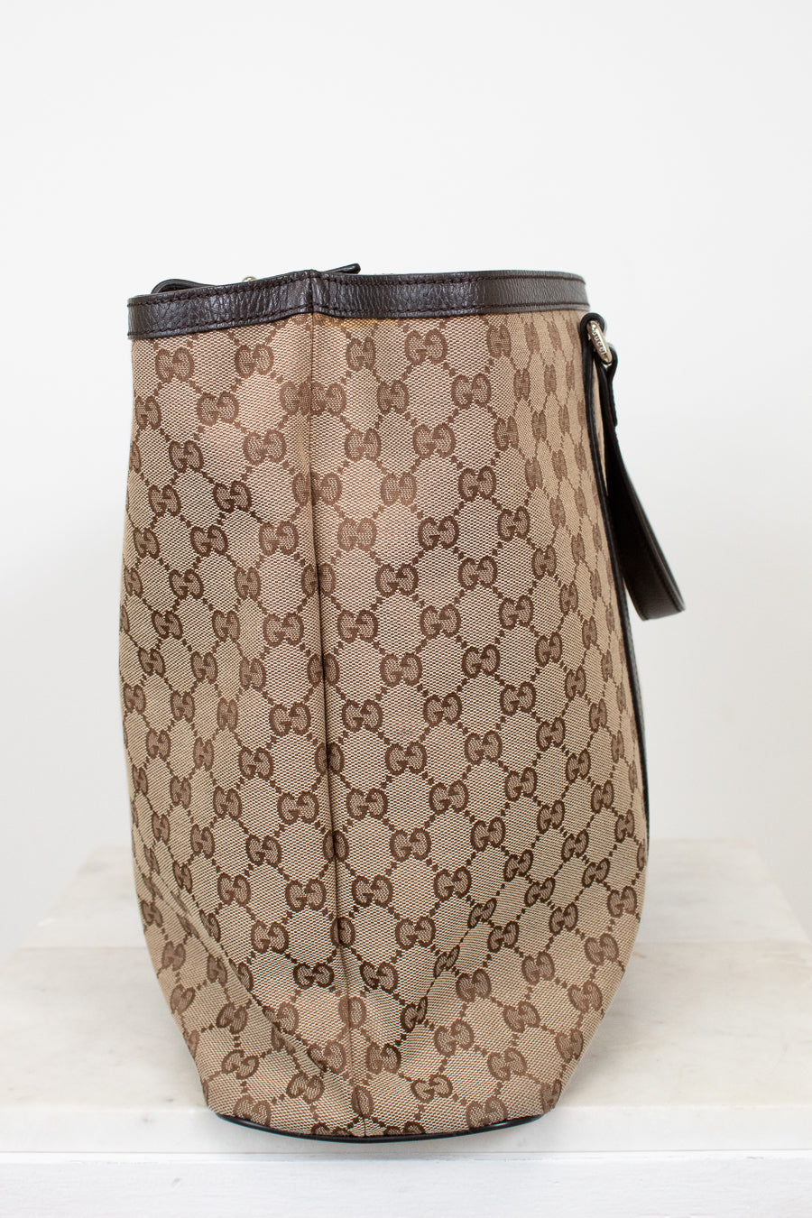 Beige and brown patterned bag with black accents on a white background