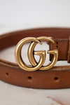 Brown leather belt with a gold Gucci buckle on a light background