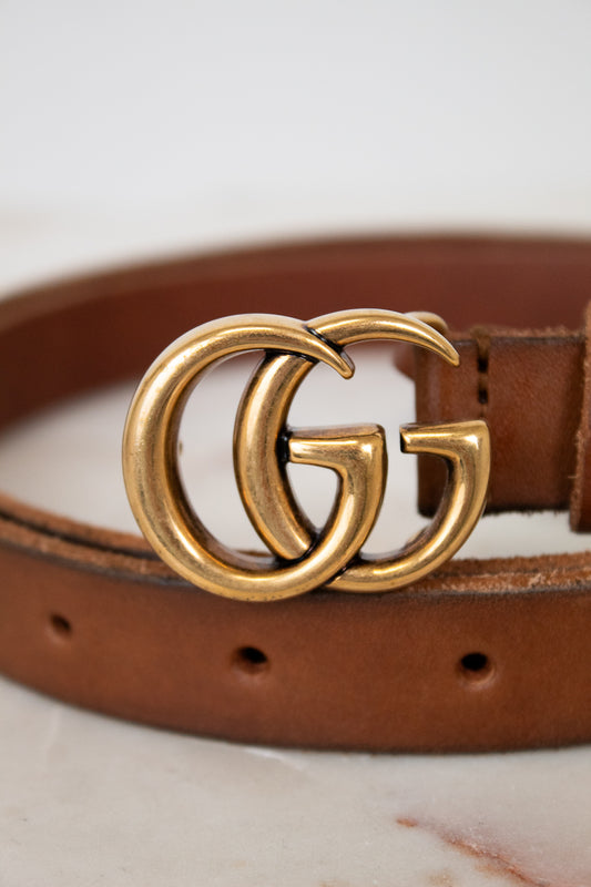 Brown leather belt with a gold Gucci buckle on a light background