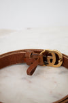 Brown leather belt with a gold buckle on a marble surface