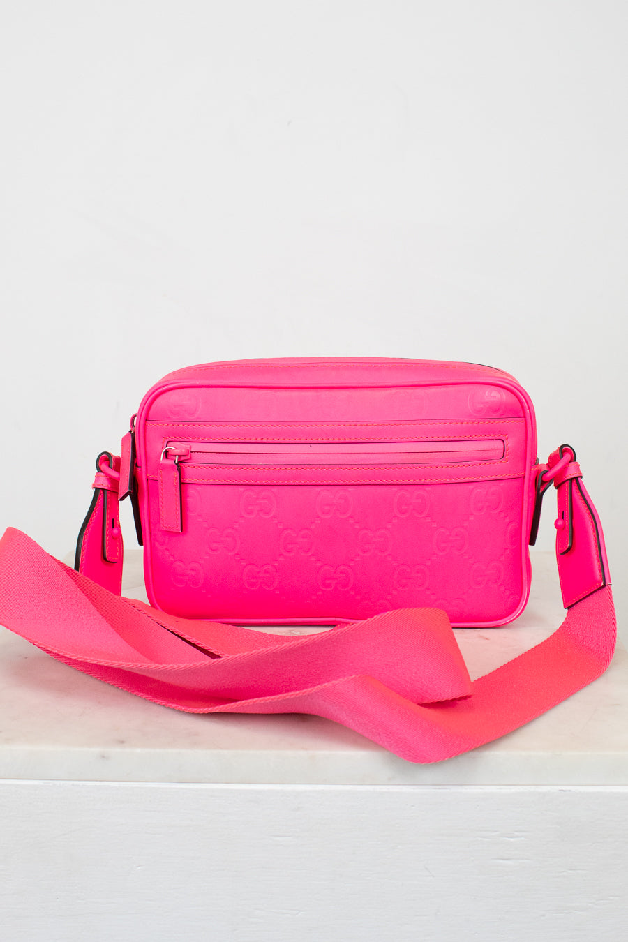 Pink crossbody bag with a strap on a white background