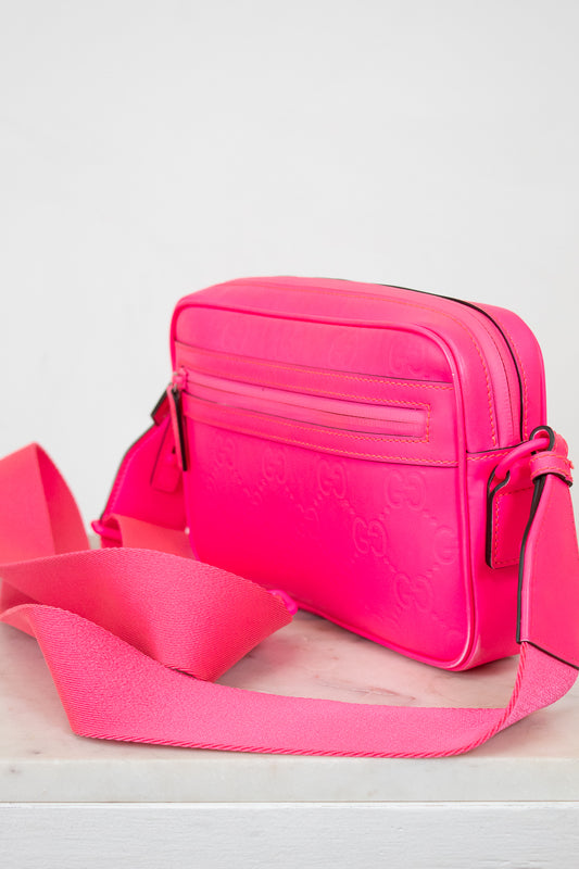 Pink handbag with a matching pink strap on a white background