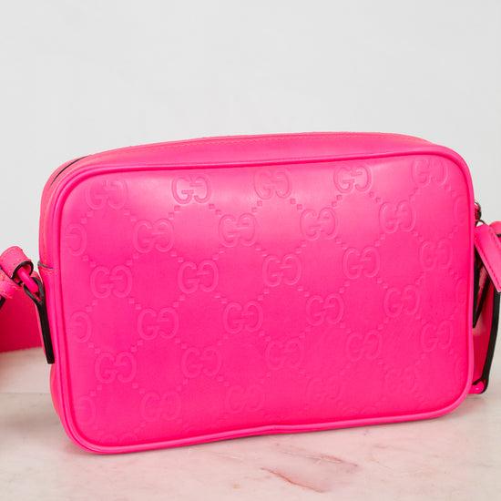 Pink Gucci bag backside on a light pink surface with a white background