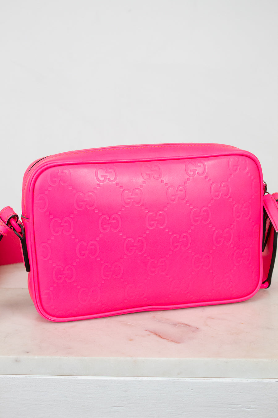 Pink Gucci bag backside on a light pink surface with a white background