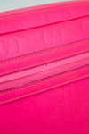 Close-up of a pink purse with stitching details on a white background