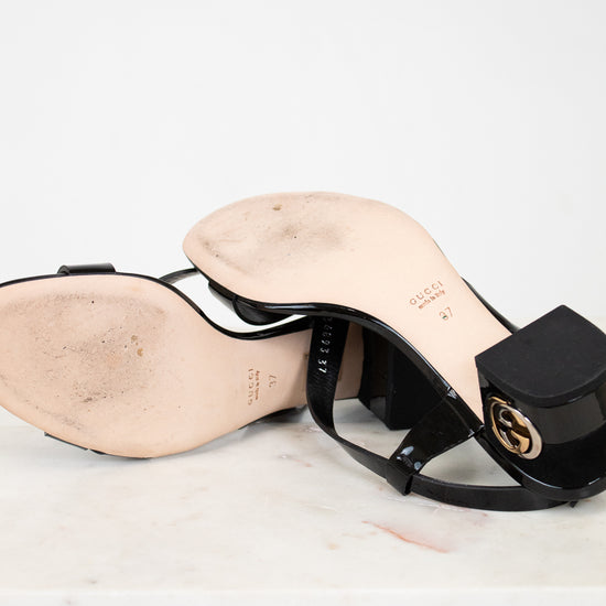 Black high-heeled sandal with a brand logo on a light background