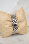 Silver watch band on a textured beige pillow with a white background