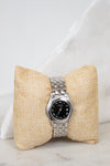 Silver watch on a textured beige pillow against a white background
