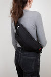 Person wearing a black Gucci bag on a plain background