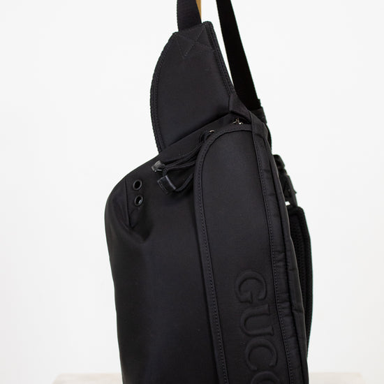 Black sling bag with Gucci logo on a white background