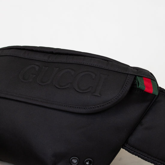 Black Gucci waist bag with logo and color stripe on a light background