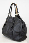 A black leather shoulder bag with an embossed monogram pattern, featuring gold-tone hardware and dual top handles, displayed on a white background.