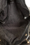 Close-up view of the interior lining of a black leather handbag, showing a dark gray patterned fabric lining with a small brand tag near the top.