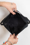 Black bag held open by hands on a white background