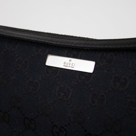 Close-up of black Gucci bag with logo pattern on a light gray background