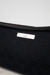 Close-up of black Gucci bag with logo pattern on a light gray background