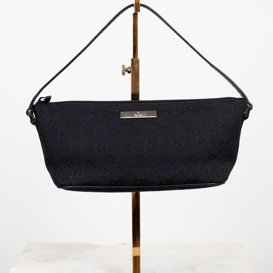 Black handbag on a gold stand against a white background
