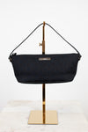 Black handbag on a gold stand against a white background