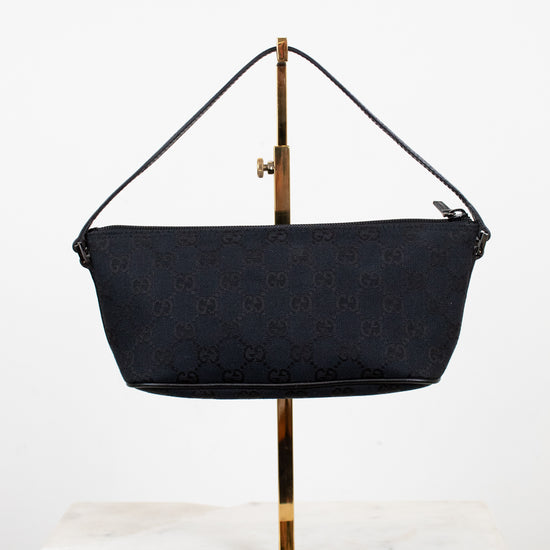 Black handbag on a gold stand against a white background
