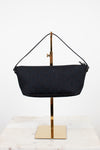 Black handbag on a gold stand against a white background