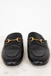 Pair of black leather slip on mules with gold hardware on a white background
