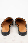 Pair of black leather mules with tan interior on a light background