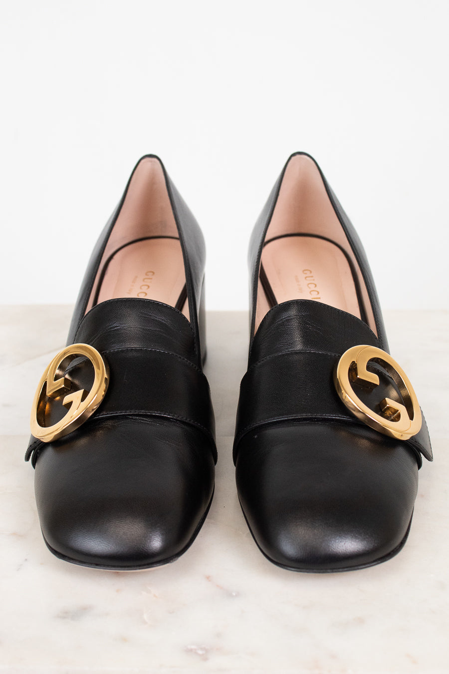 Front view of black leather loafers showing round toe and gold 'GG' logo hardware