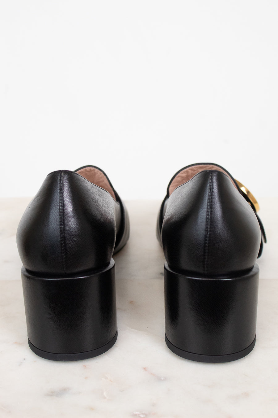 Heel view showing chunky heel of black leather loafers