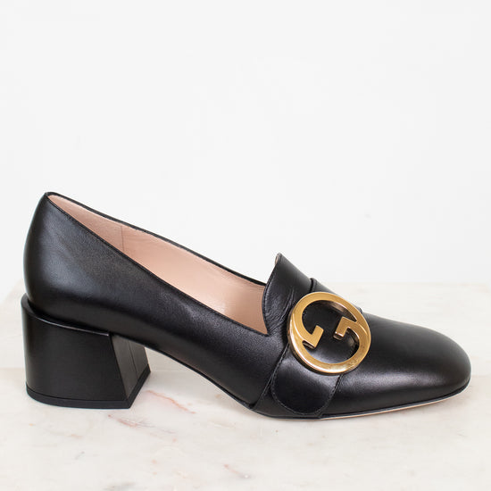 Side view of black leather loafer with chunky heel showing gold 'GG' logo and against a plain background