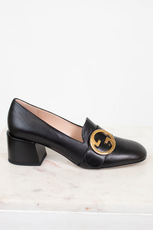 Side view of black leather loafer with chunky heel showing gold 'GG' logo and against a plain background