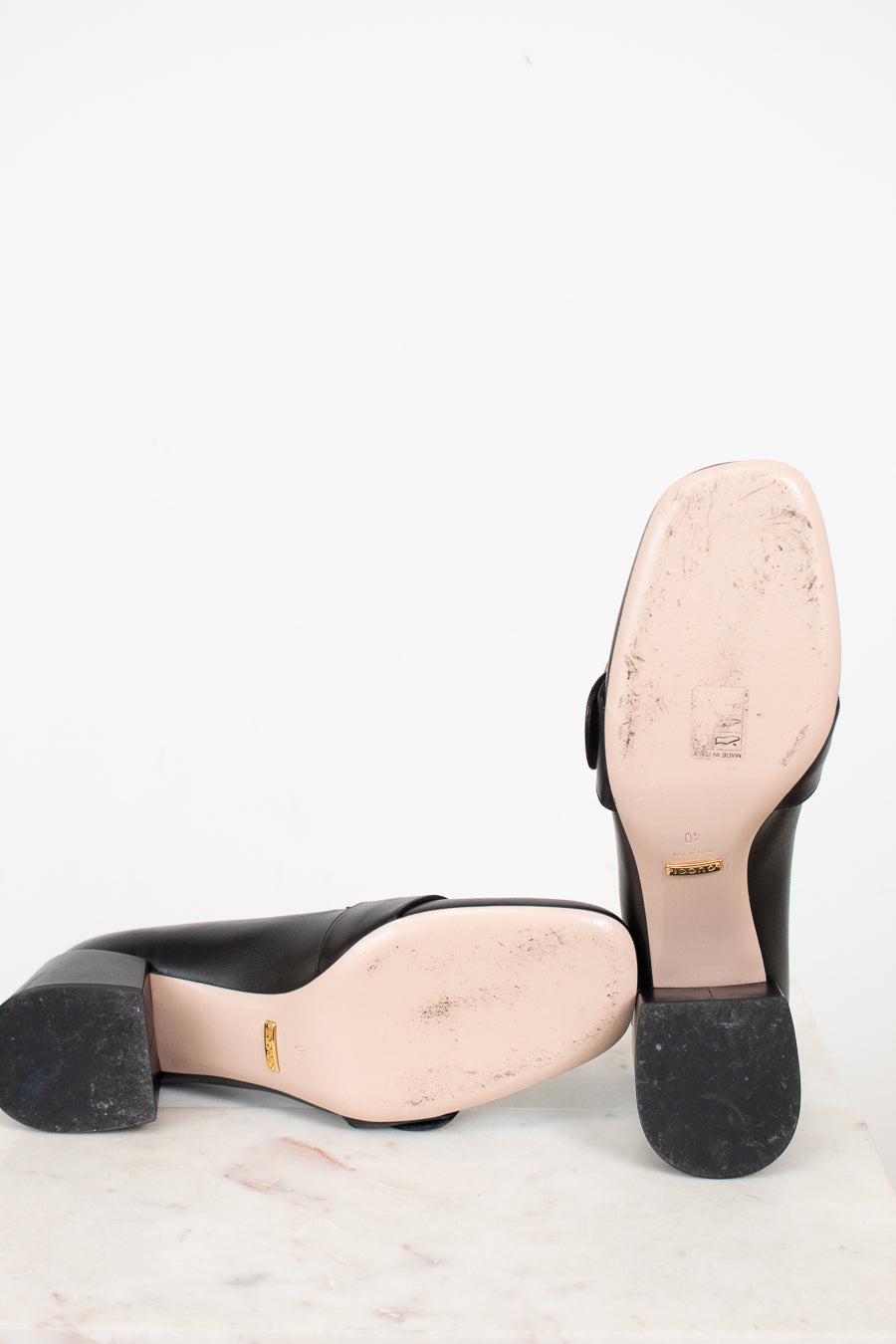 Bottom exterior sole view of chunky heeled shoes laying against a plain background